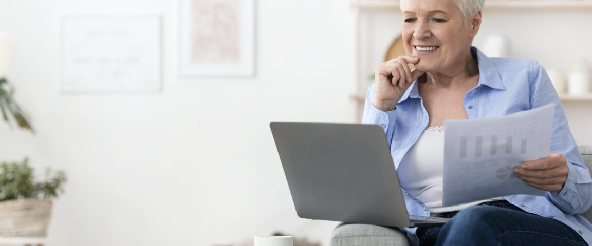 Confident senior woman working with laptop and papers at home